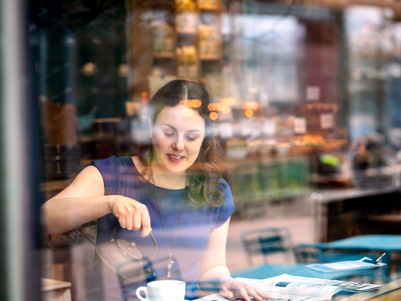 Thriller author Nicola Martin sitting in a cafe pouring tea